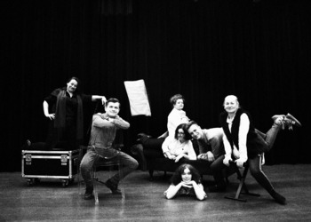 Czarno-białe zdjęcie przedstawiające 7osób w różnych pozycjach na scenie.